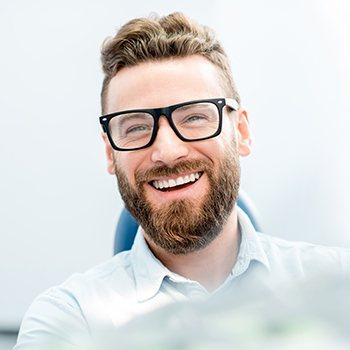 Man with glasses smiling in dental office