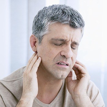 Man holding jaw joints in need of TMJ therapy