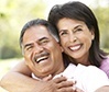Older man and woman smiling outdoors after restorative dentistry