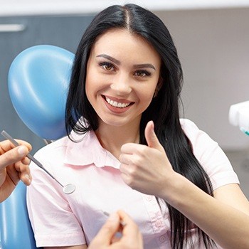 Woman in dental chair giving thumbs up