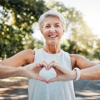 Lady smiles while making shape of heart with her hands