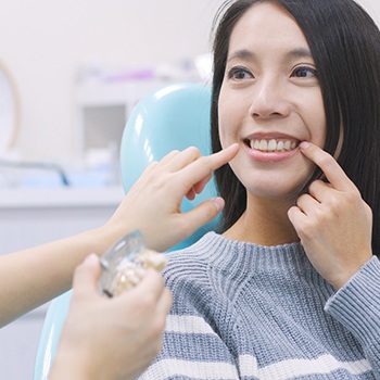 Woman pointing to her smile during dental implant consultation