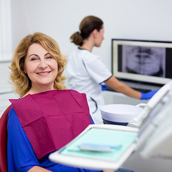 Middle-aged woman smiling while sitting in dental chair