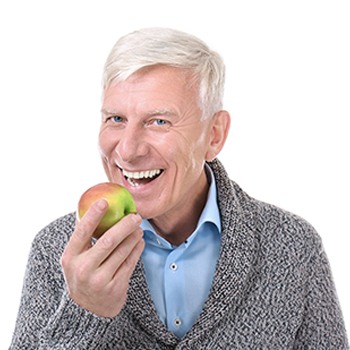 Older man in sweater eating an apple