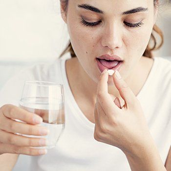 Woman taking antibiotic pill to combat gum disease