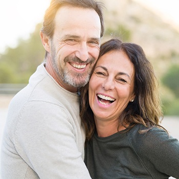 An older couple smiling outside.