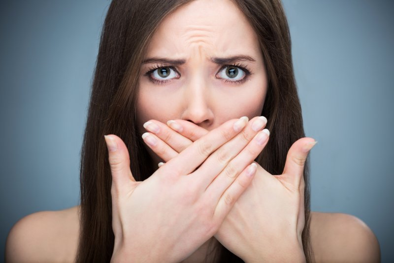 Woman with bad breath covering mouth