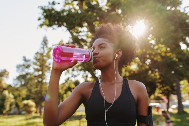 Woman drinking water during the summertime to stay hydrated.