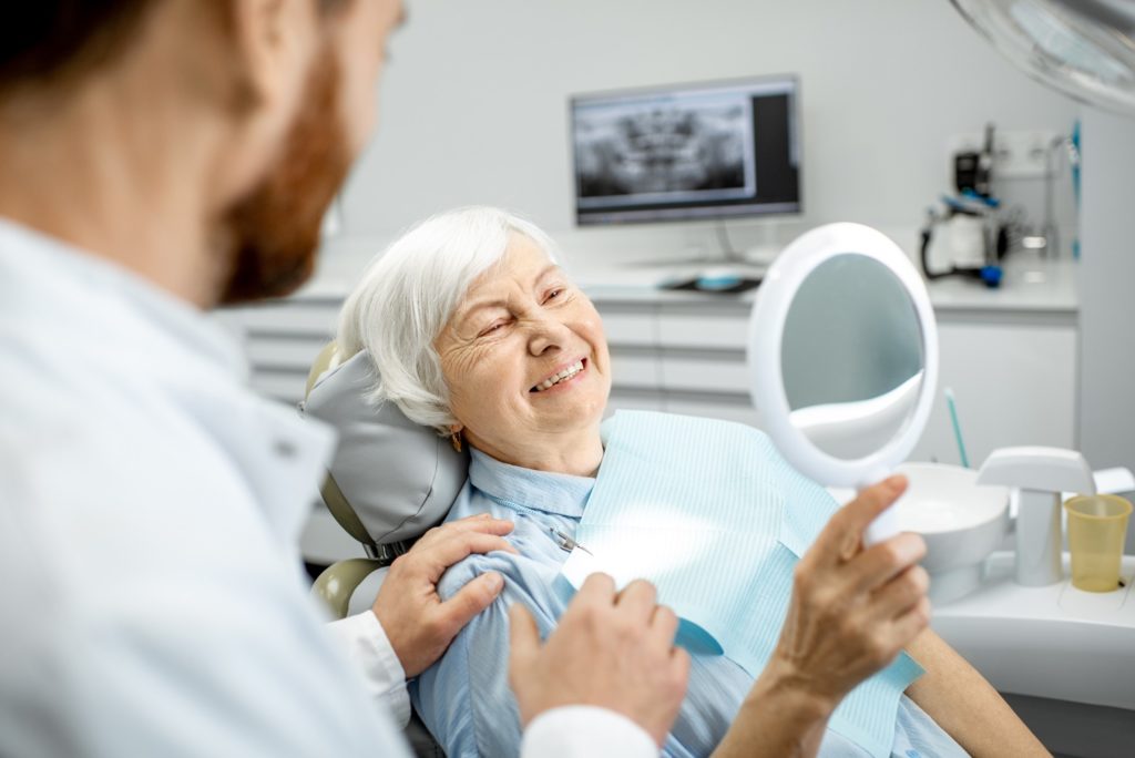 Woman smiling in mirror after dental checkup