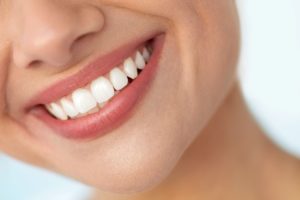 Closeup of face nose down with smiling white teeth in front of a white background