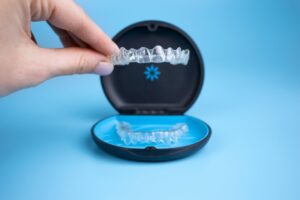 Hand holding up Invisalign clear aligners. 